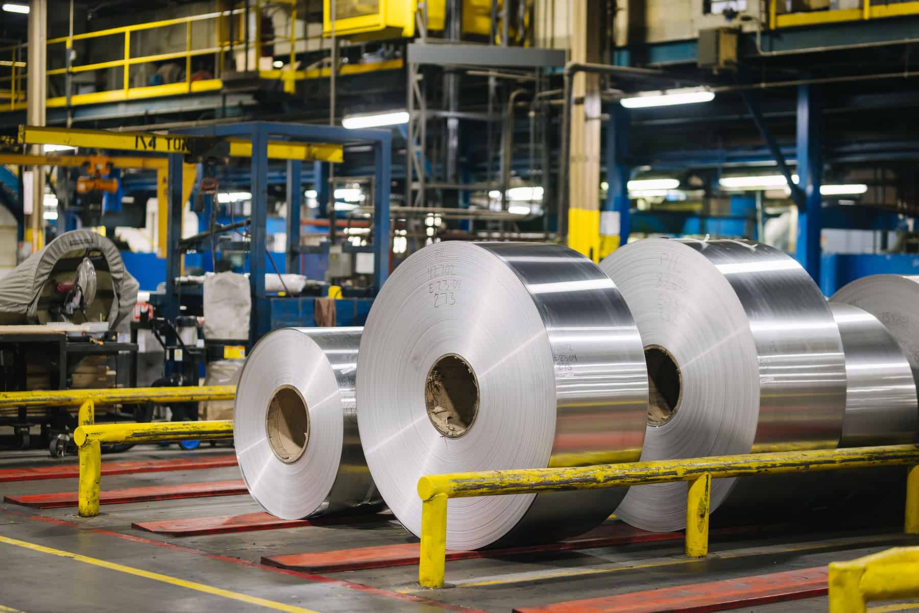 Stacked coils of rolled aluminum in a factory warehouse, poised for further manufacturing uses.