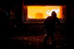 Man in safety gear approaching a furnace to melt Aluminum Sheet.