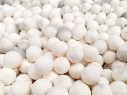 Manufacturer's white alumina balls after refining bauxite: beads and pellets background.