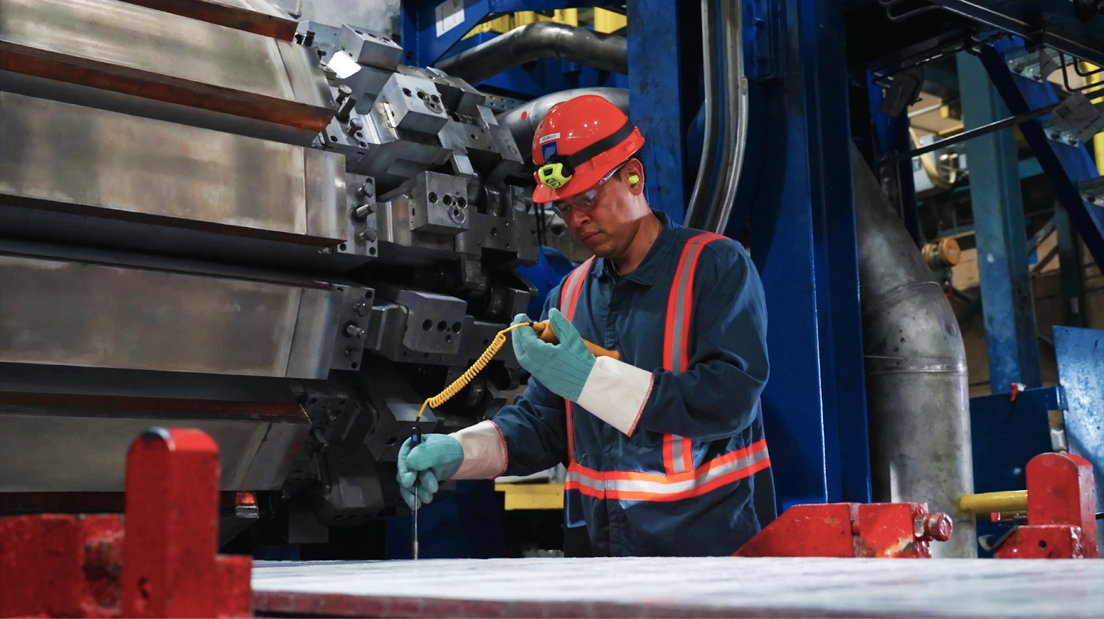 Engineer wearing safety gear inspecting aluminum casting equipment inside a Golden Aluminum production facility.
