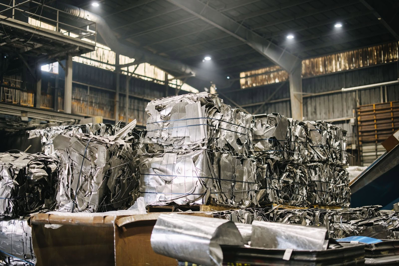 Compressed aluminum scrap bales staged inside a mill warehouse for recycling and reuse.